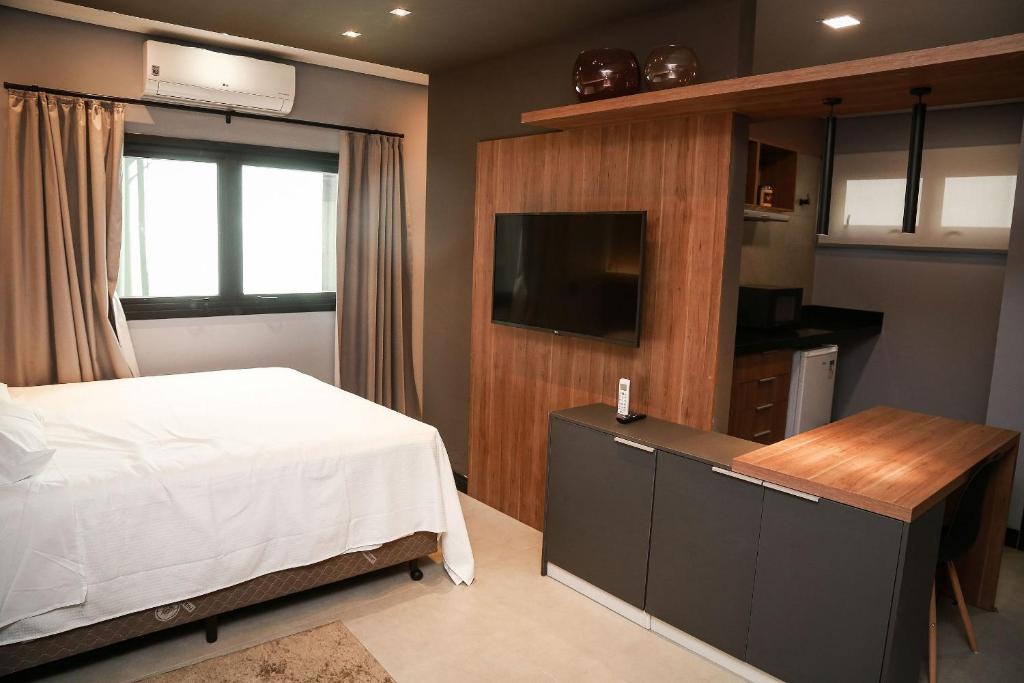 1 dormitorio con 1 cama y TV de pantalla plana en Globo Lar Studios en Limeira