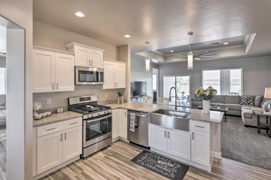 a kitchen with white cabinets and a living room at Idyllic Kingman Retreat with Yard - Near Hiking in Kingman