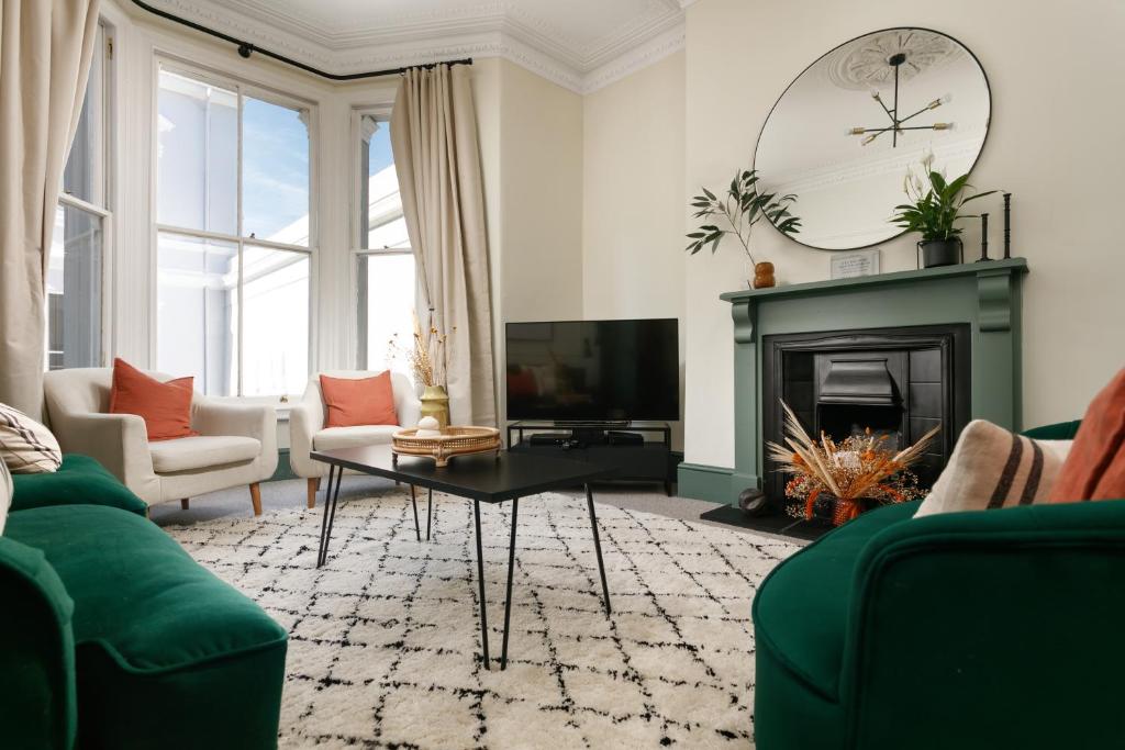 a living room with a green couch and a fireplace at NEW LUXURY for 2022 - Central Plymouth House - Sleeps 10 - Access to Plymouth Hoe - Close to The Barbican - Pets welcome - By Luxe Living in Plymouth