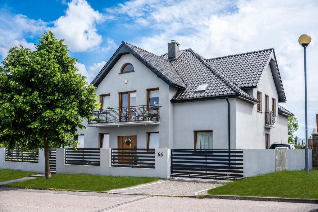 a white house with a black roof at SeaEsta Darłowo - Komfortowe Pokoje i Apartamenty in Darłowo