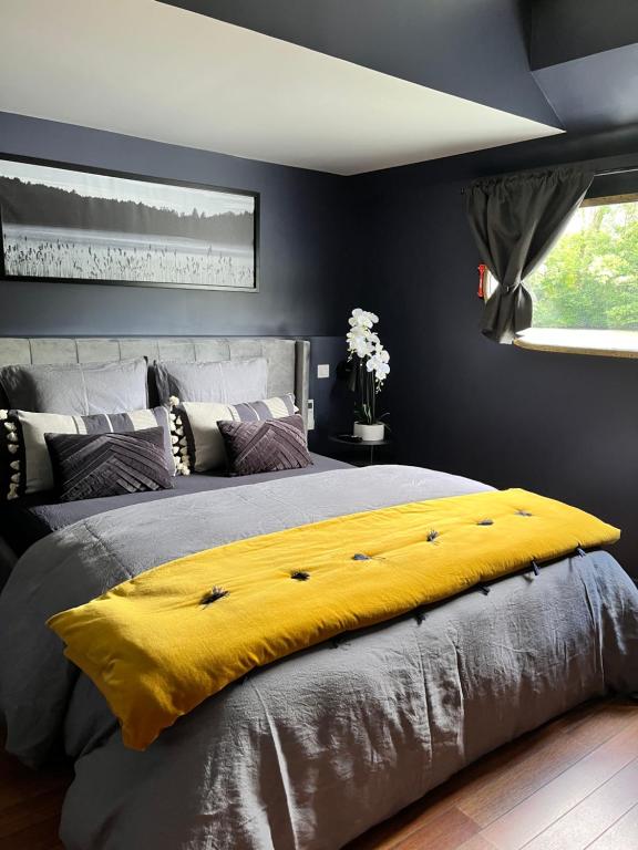 a bedroom with a large bed with a yellow blanket at Péniche Santa Julia au port de Chantilly Insolys in Saint-Leu-dʼEsserent
