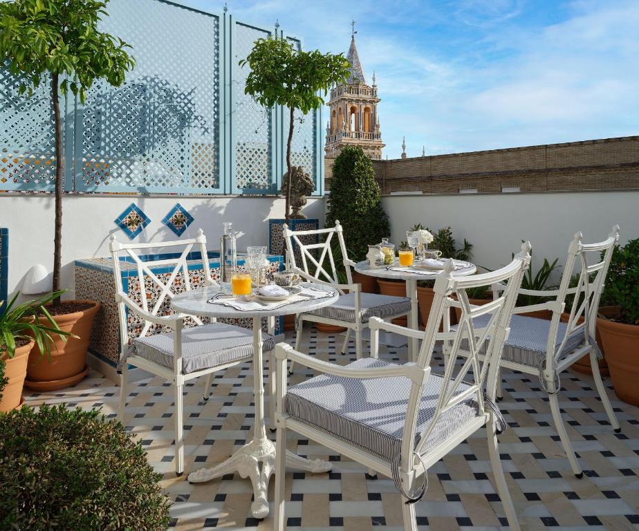 une table et des chaises sur une terrasse avec une tour d'horloge dans l'établissement Hotel Boutique Triana House, à Séville