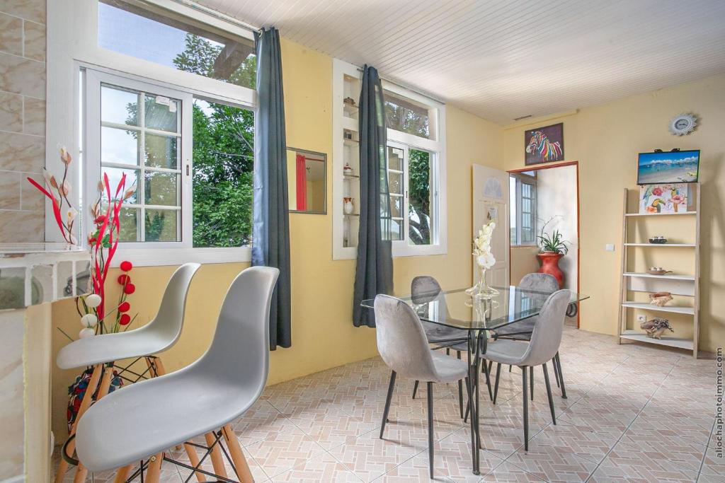 una sala da pranzo con tavolo in vetro e sedie di Appartement La Source -Calme avec belle vue mer a Les Trois-Îlets