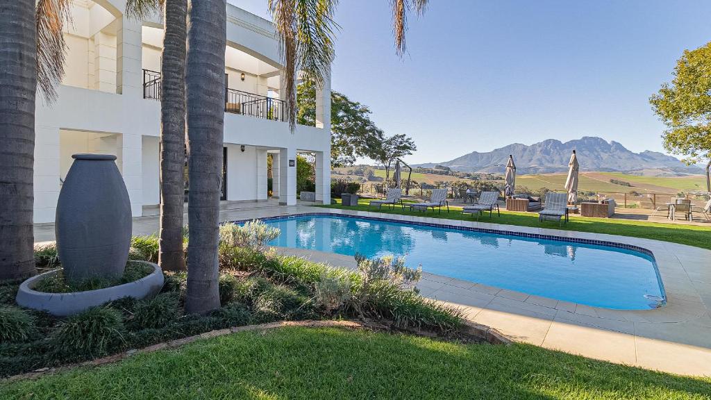 a swimming pool in front of a house with a palm tree at The Salene Hotel & Cottages in Stellenbosch
