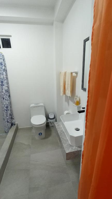 a white bathroom with a toilet and a sink at Hotel Ola Bella in San Clemente