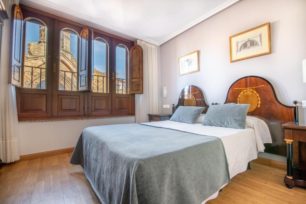 a bedroom with two beds and a large window at Hospedium Plaza Mayor Salamanca in Salamanca