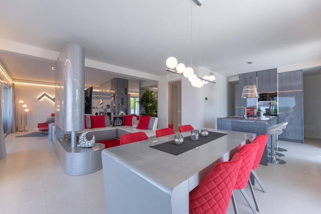 a kitchen and living room with a table and red chairs at Magic Luxury Apartments in Bardolino