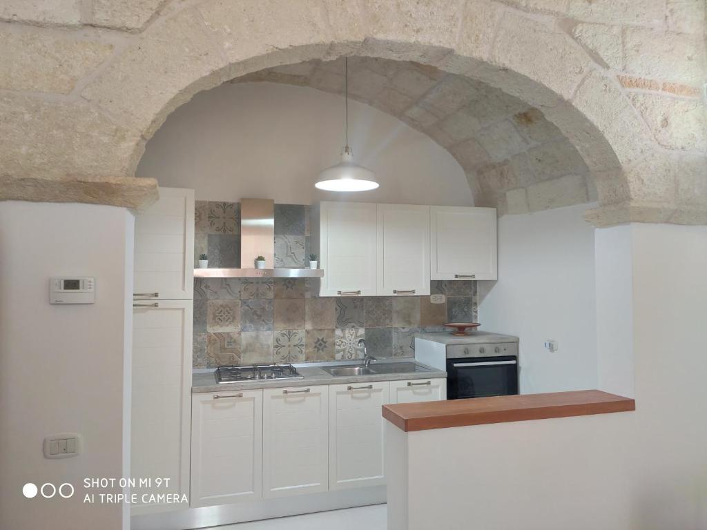 una cucina con armadi bianchi e un muro in pietra di Casa Di Antonio a Polignano a Mare