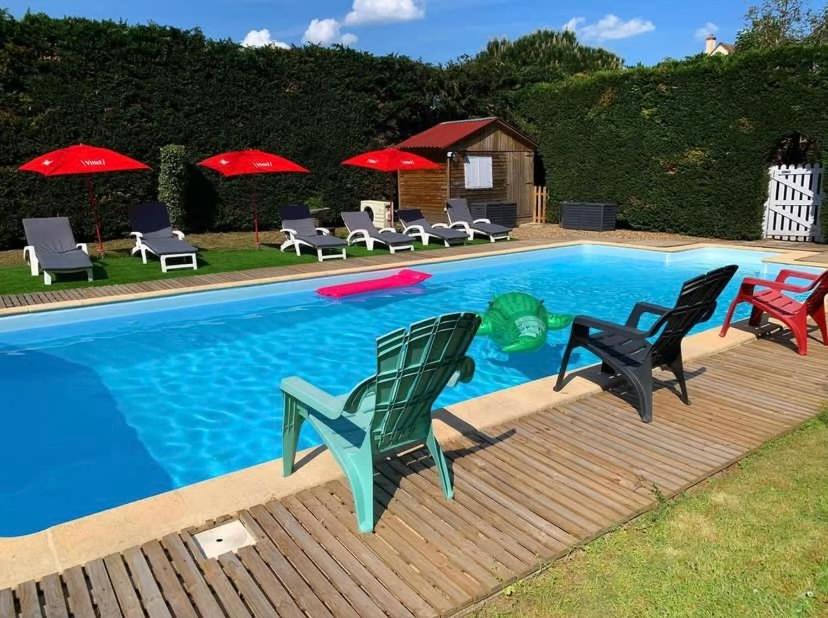 ein Pool mit Stühlen und Sonnenschirmen daneben in der Unterkunft Le Clos des Trois Provinces, Zoo de Beauval in Noyers-sur-Cher