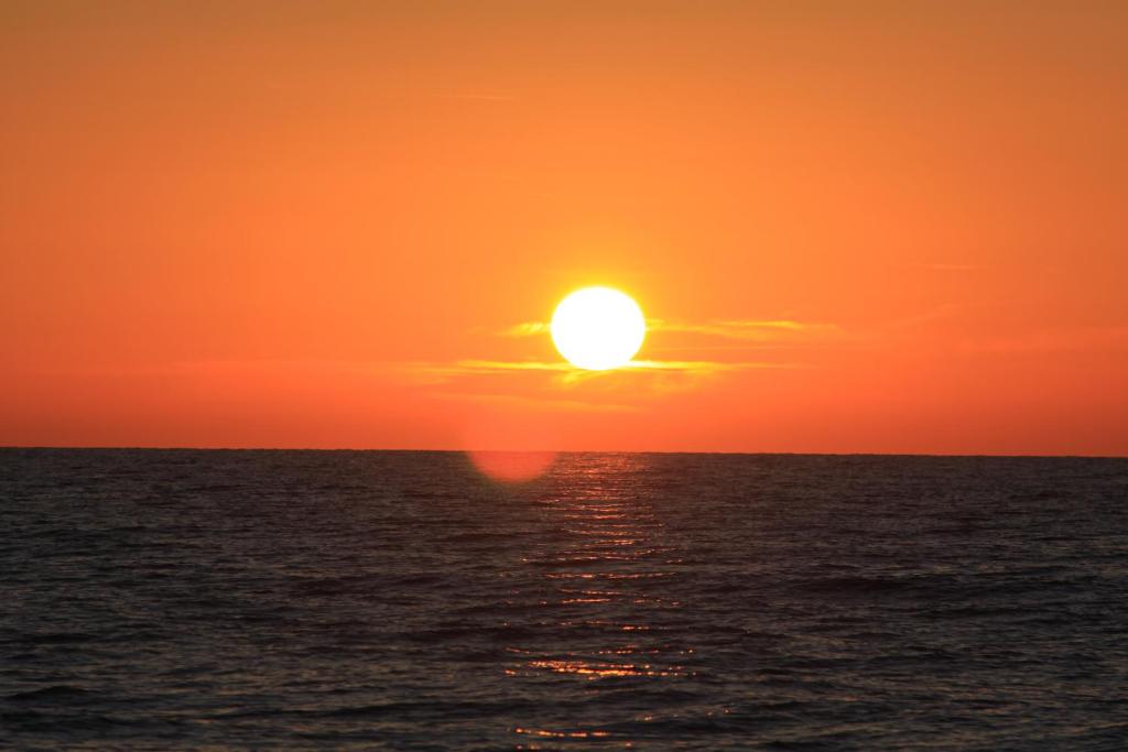 a sunset over the ocean with the sun in the sky at Apartament DINO in Ustka