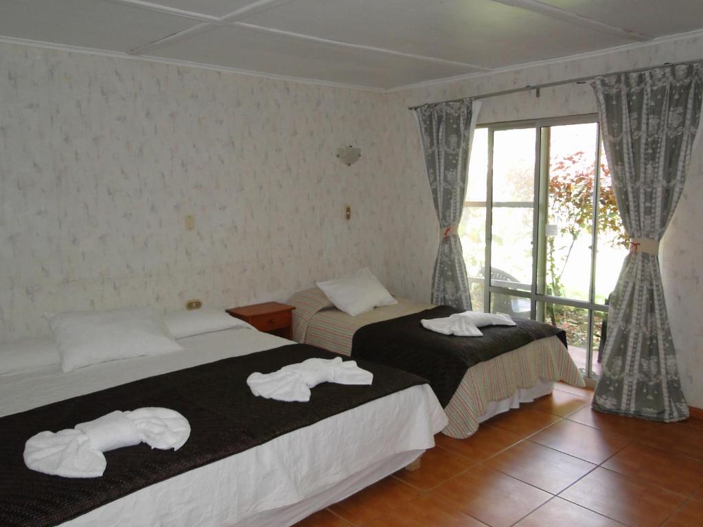 two beds in a room with towels on them at Tupa Hotel in Hanga Roa