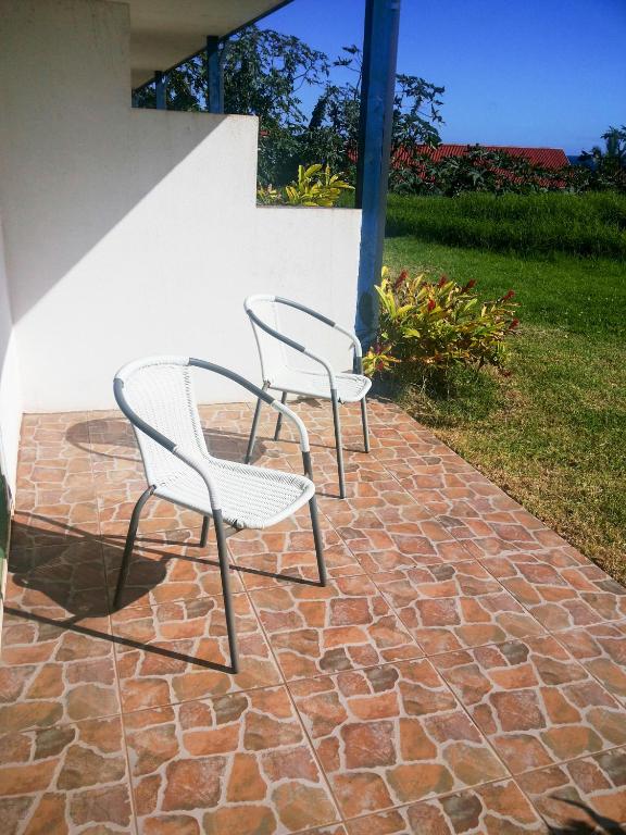 two white chairs sitting on a brick patio at Tupa Hotel in Hanga Roa