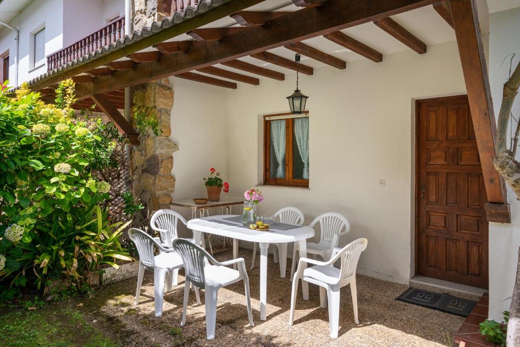 patio z białym stołem i krzesłami oraz drewnianymi drzwiami w obiekcie Casa de playa toró w mieście La Portilla