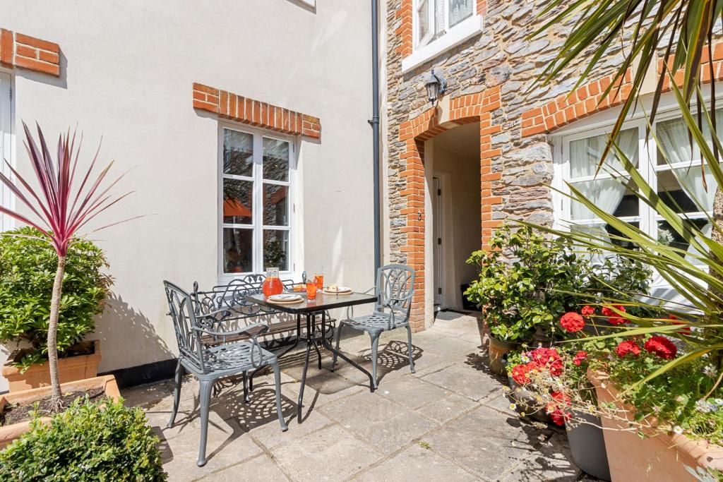 a patio with a table and chairs and plants at Old Mill Court, Brixham in Brixham