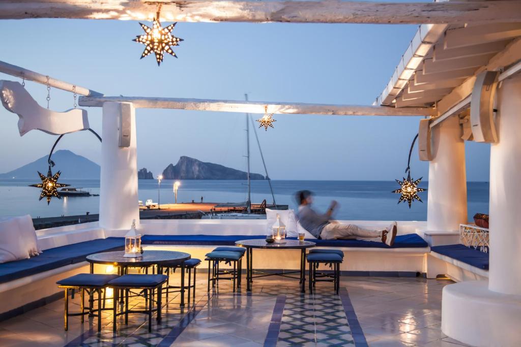 a room with tables and chairs and a view of the ocean at Hotel Lisca Bianca in Panarea