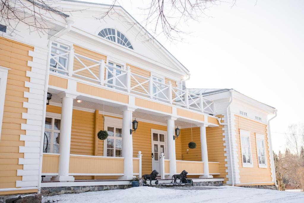 une maison jaune et blanche avec colonnes blanches dans l'établissement Tiittalan Kartano, à Sulkava