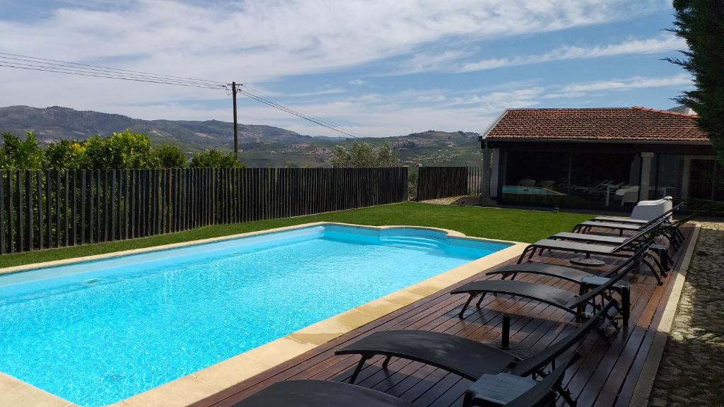 a swimming pool with chairs next to a house at Casa Nª Sra. do Carmo in Peso da Régua