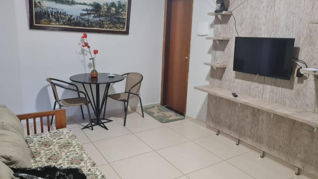 sala de estar con mesa y TV en la pared en APARTAMENTOS NO CENTRO DE BRASILIA., en Brasilia