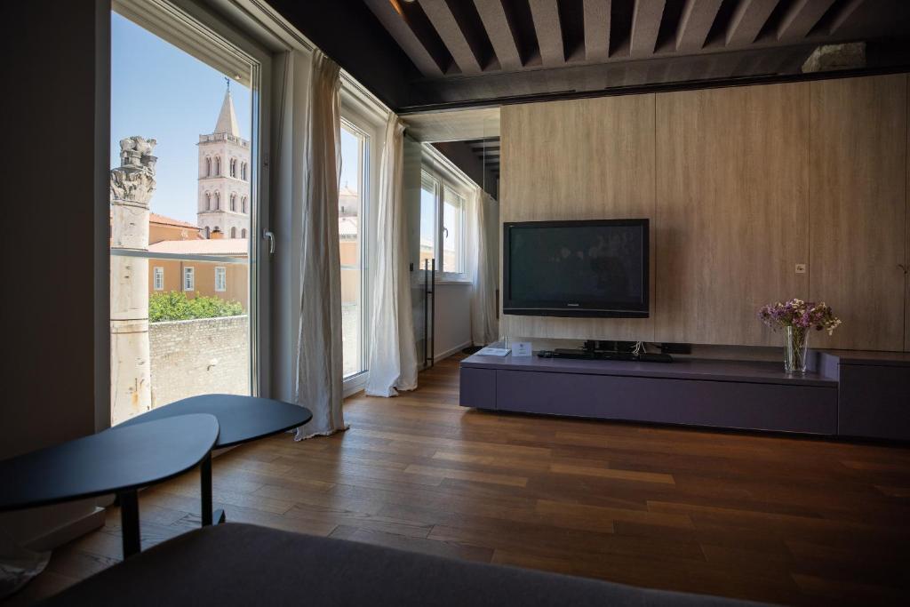 een woonkamer met een tv en een groot raam bij Apartment F in Zadar