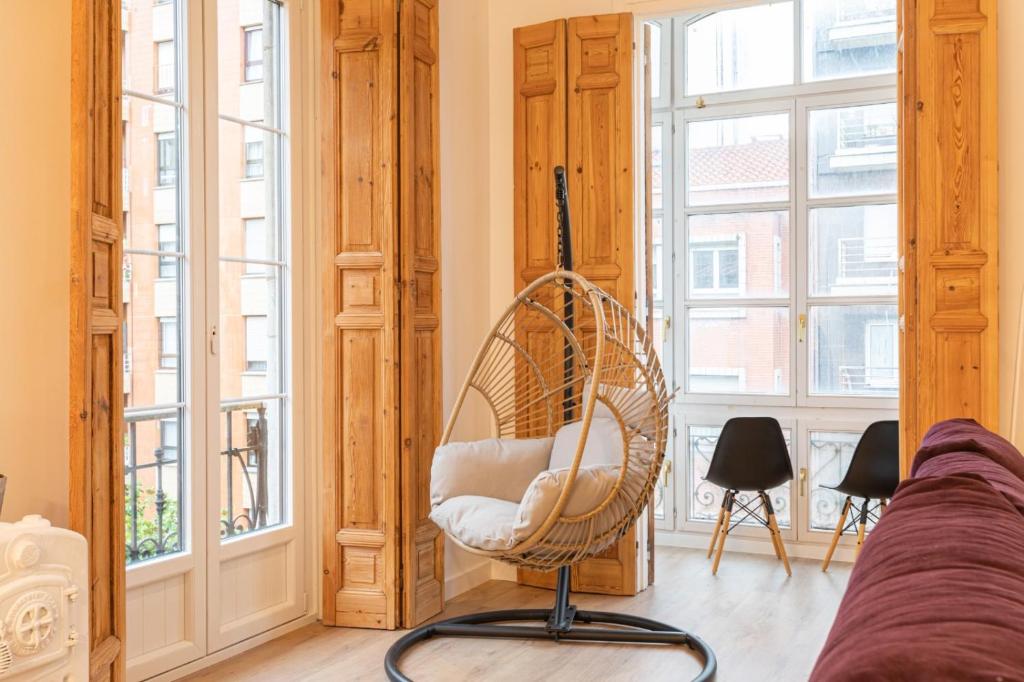 una sedia in vimini seduta in una stanza con finestre di Lujo, comodidad y espacio Gijon centro a Gijón
