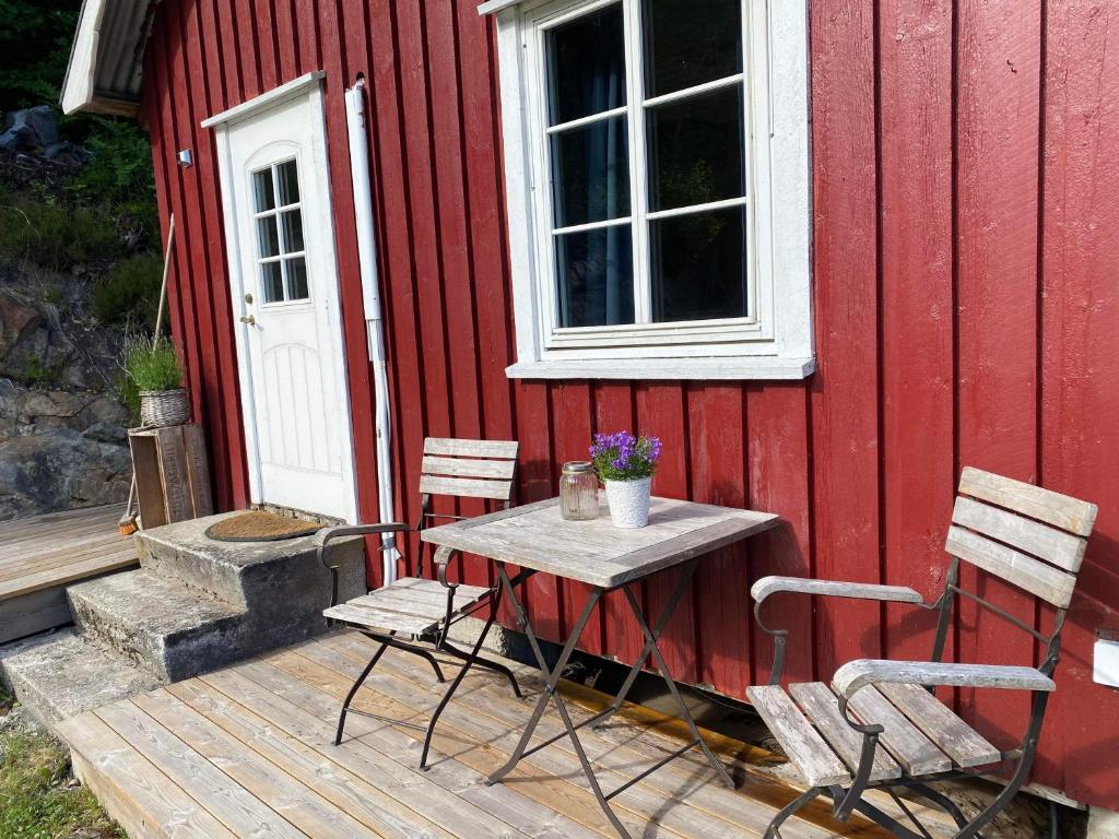 een tafel en stoelen op een terras naast een rood gebouw bij Bryggerhus Og Leilighet in Kragerø