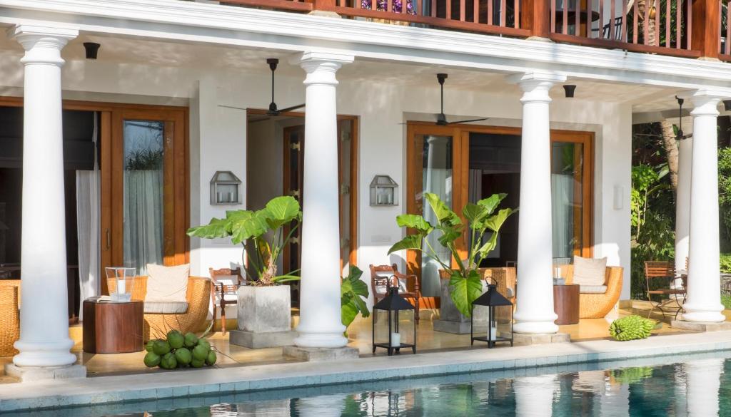 a villa with a swimming pool in front of a house at Eraeliya Villas & Gardens in Weligama