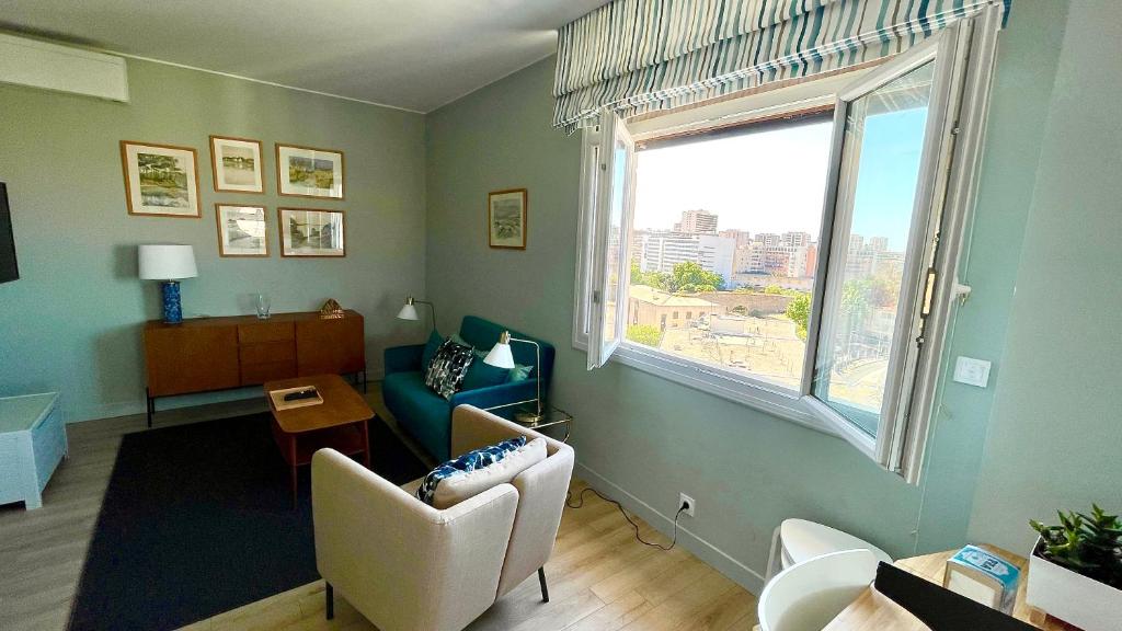 a living room with a couch and a window at Vue sur rade appartement élégant vaste climatisé étage élevé ascenseur proche parking et toutes commodités au cœur du Toulon historique in Toulon