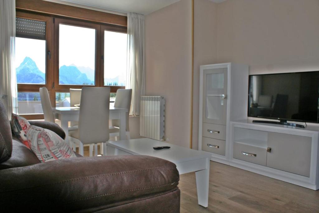 Una sala de estar con un sofá, un televisor y una mesa. en Los Casares, en Riaño