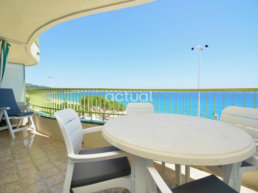 een witte tafel en stoelen op een balkon met uitzicht op de oceaan bij Super Beach 3B in Platja  d'Aro