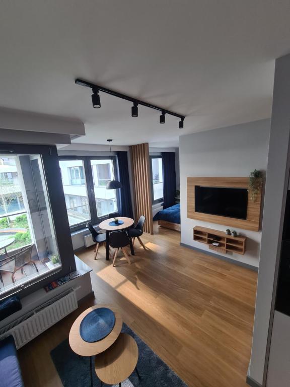 sala de estar con TV, mesa y sillas en Sea Apartament - Plac Unii, en Gdynia