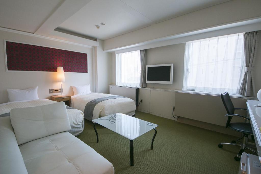 um quarto de hotel com duas camas e um sofá em Grand Park Hotel EX Fukushimaebisu em Fukushima