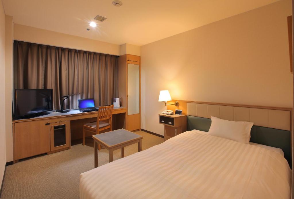 a hotel room with a bed and a television at Odakyu Station Hotel Hon-Atsugi in Atsugi