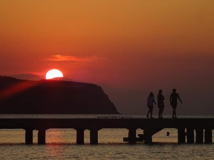 two people walking on a pier with the sunset in the background at Sunset view Rooms in Agia Triada