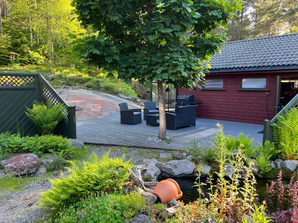 una terrazza in legno con sedie e un albero in giardino di Oggevatn a Birkenes