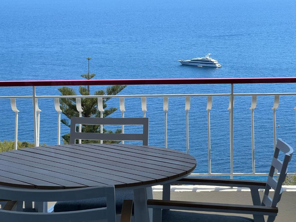 einen Tisch und Stühle auf einem Balkon mit einem Boot im Wasser in der Unterkunft MyBlueVista LUXURY PANORAMIC SEA VIEW APARTMENTS CAP D AIL NEAR MONACO in Cap d'Ail