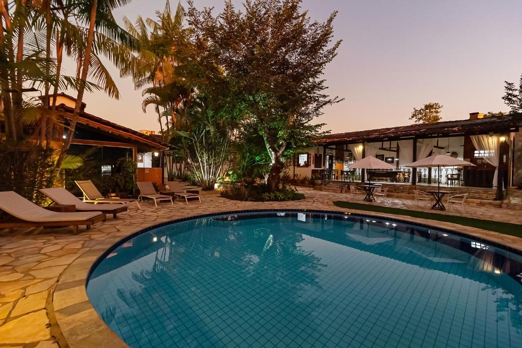 a swimming pool with chairs and a house at Pousada Arvoredo in Pirenópolis