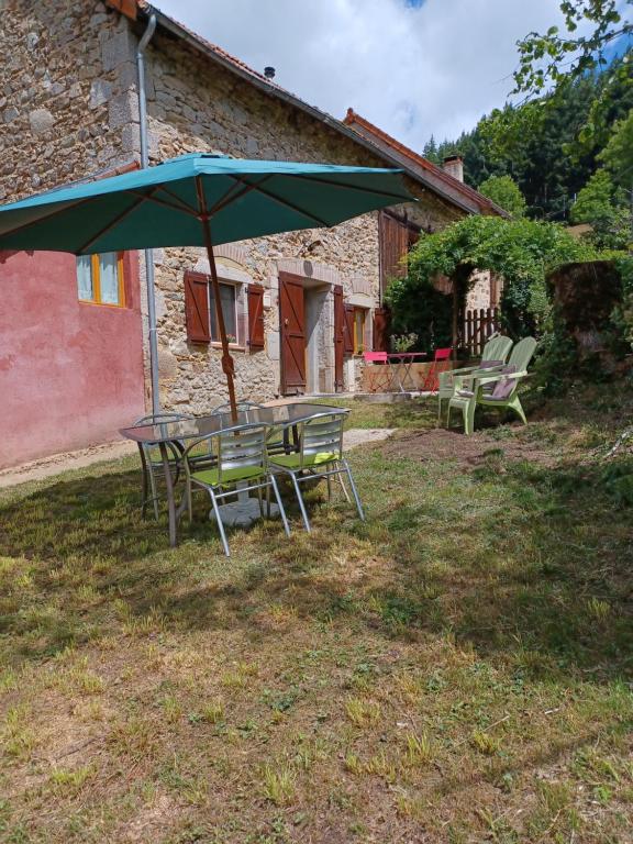 stół i krzesła z parasolem na dziedzińcu w obiekcie Gite un bout du sud w mieście Châtel-Montagne