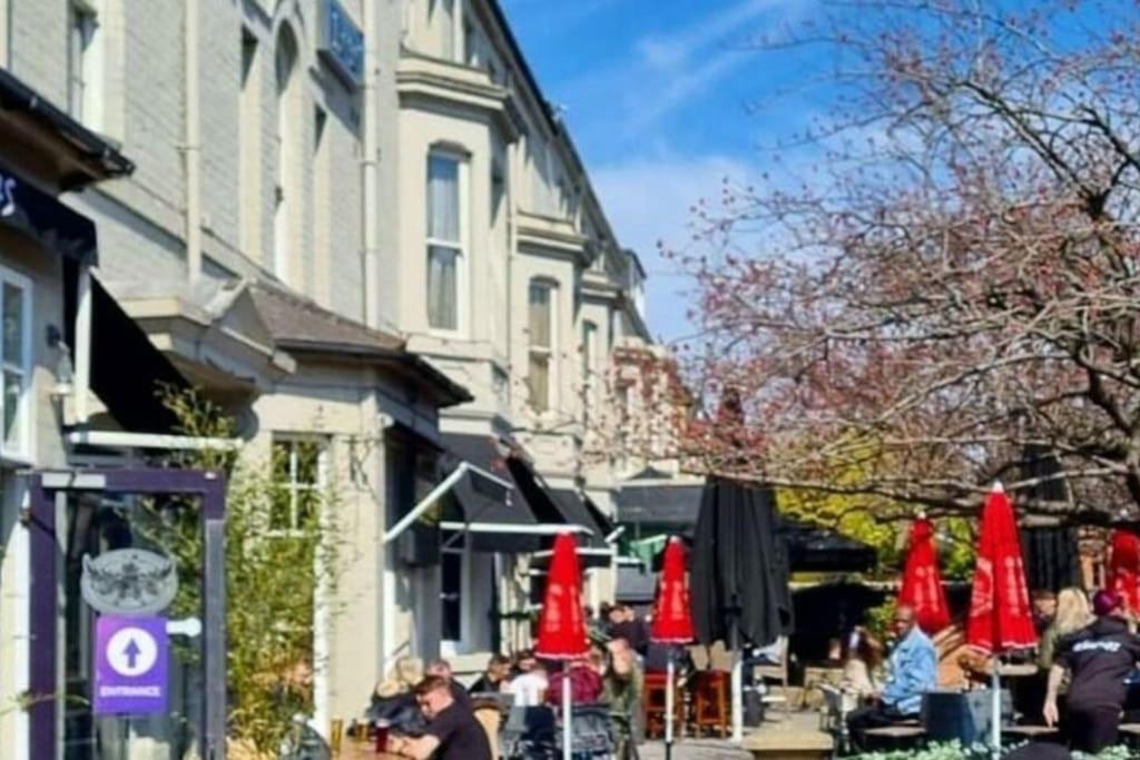 a group of tables with red umbrellas next to a building at Cosy Jesmond 3 bed apartment - fantastic location in Jesmond