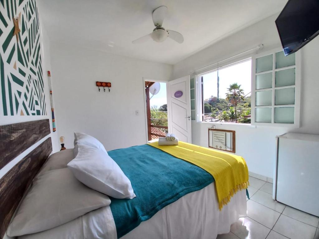 um quarto com uma cama com um cobertor amarelo e azul em Casa Colomba em Búzios