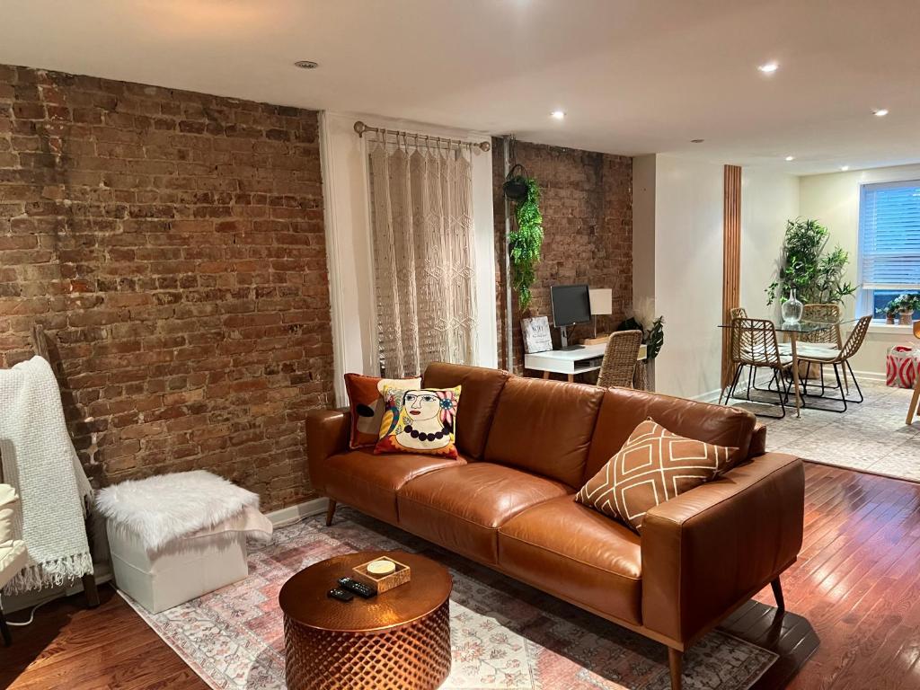 a living room with a brown couch and a brick wall at LUXE BROOKLYN Getaway in Brooklyn