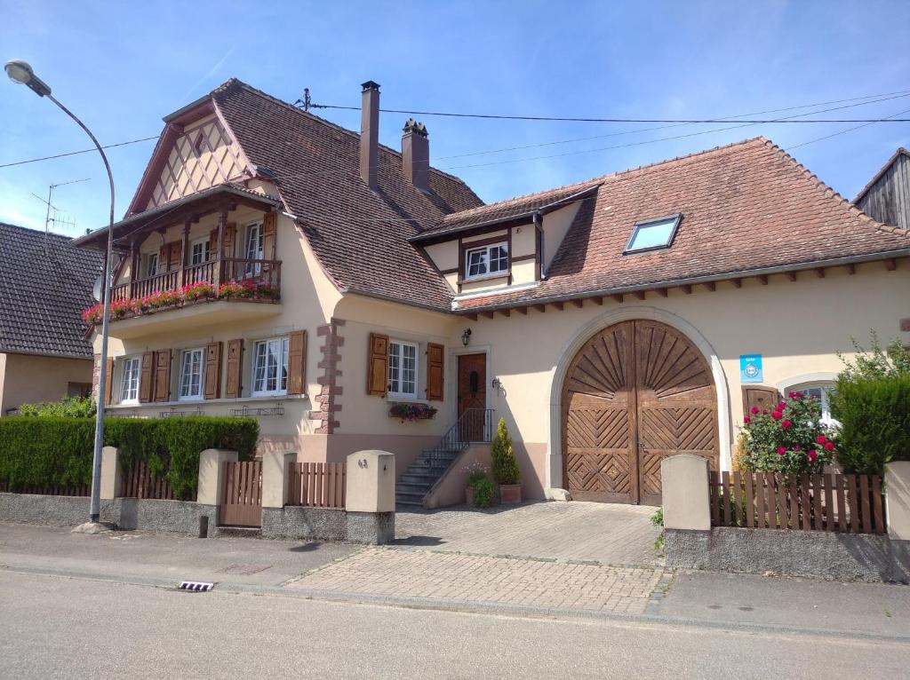 una casa bianca con una grande porta in legno di Gites les cocottes a Zellwiller