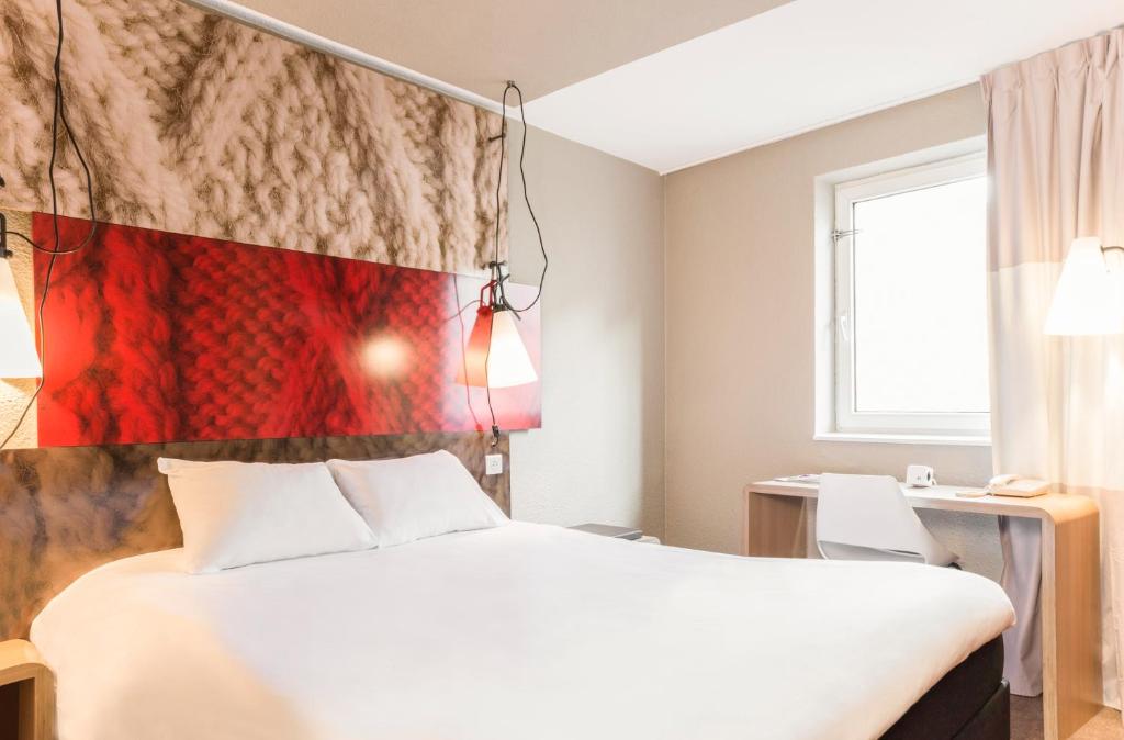 a hotel room with a bed and a flag on the wall at ibis Issy les Moulineaux "Val de Seine" in Issy-les-Moulineaux