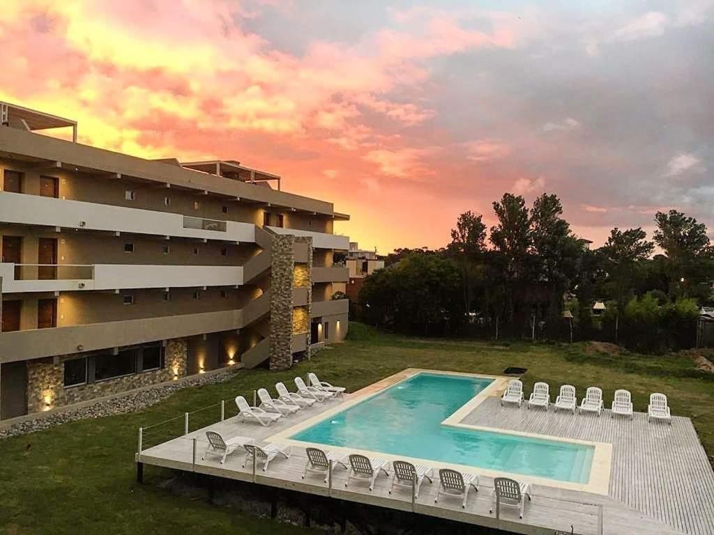 een resort met een zwembad en stoelen en een gebouw bij Agua 22 in Mar de las Pampas