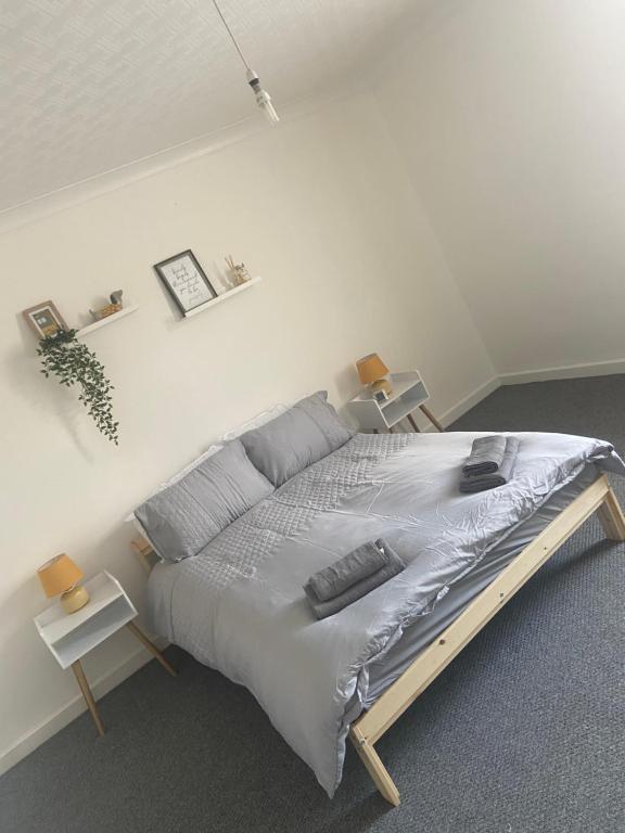 ein großes Bett in einem weißen Schlafzimmer mit 2 Tischen in der Unterkunft Cheerful 2 bedroom house in Hindley