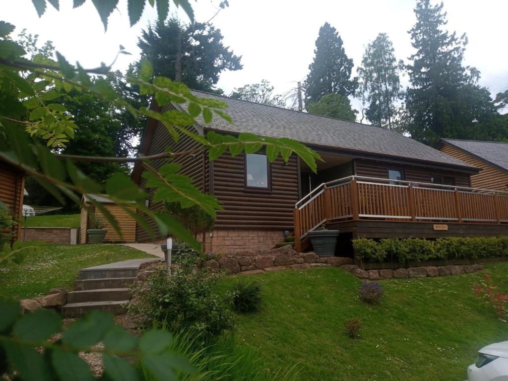 una casa de madera con terraza y patio en Charming lodge cosy comfortable ideal location, en Blairgowrie