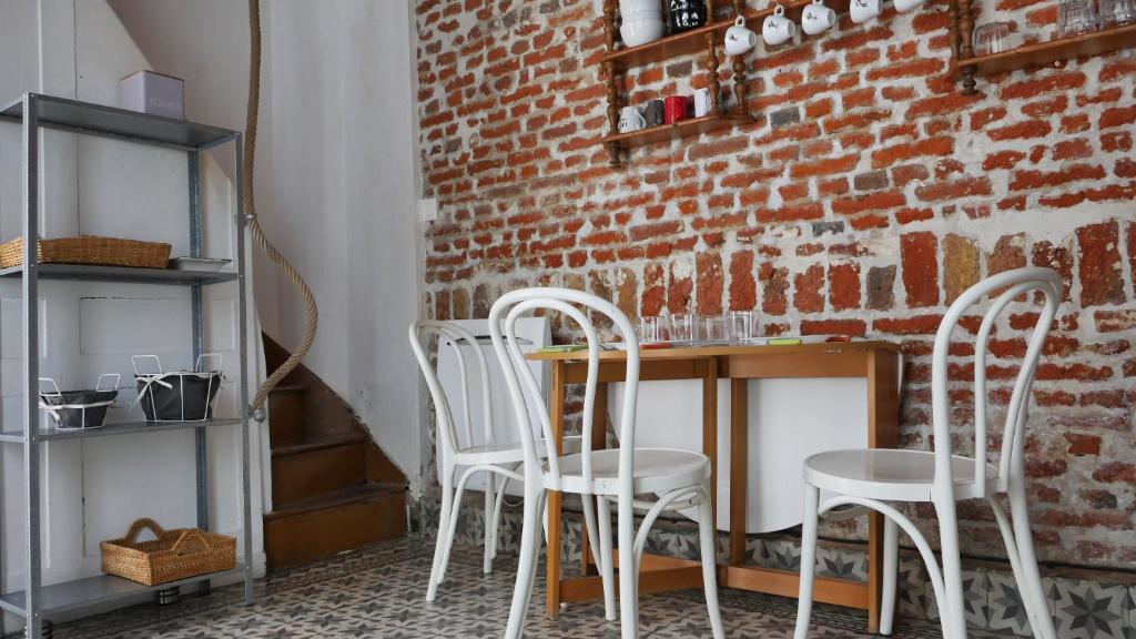 a brick wall with three white chairs and a table at Au charme d'antan en plein coeur du vieux Lille in Lille