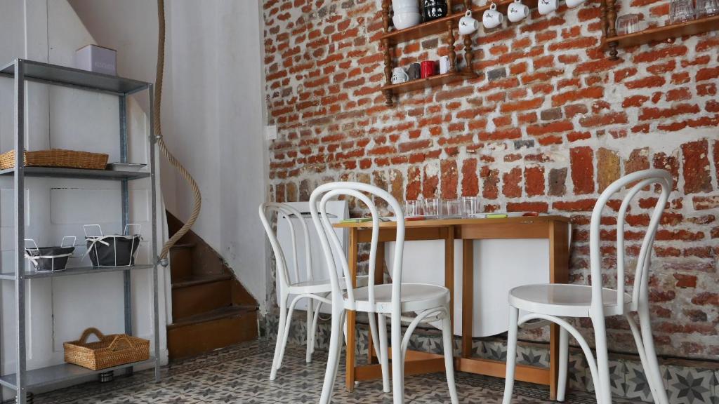 un mur en briques avec trois chaises blanches et une table dans l'établissement Au charme d'antan en plein coeur du vieux Lille, à Lille