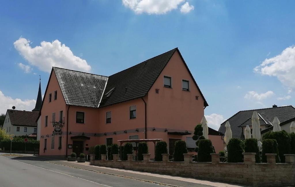 a pink house with a black roof on a street at Landgasthof Niebler in Adelsdorf