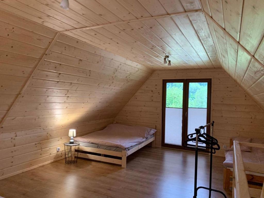 Domek u Kamińskich في Przyborów: غرفة مع سرير في العلية مع نافذة