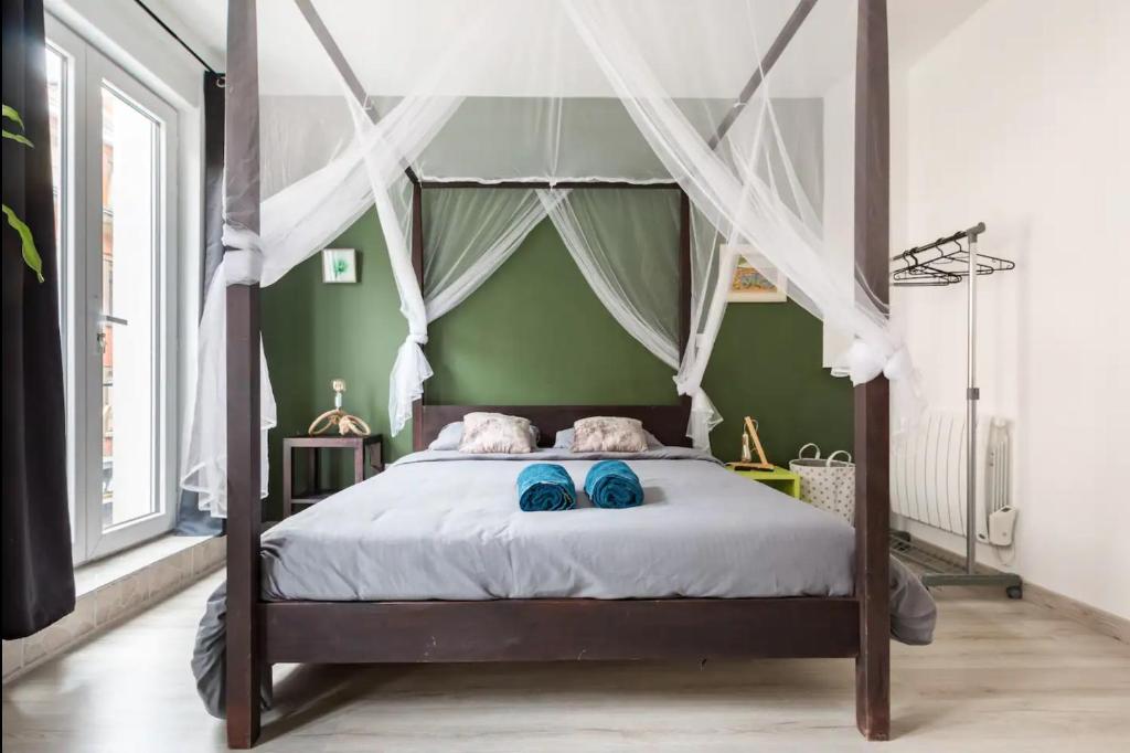 ein Schlafzimmer mit einem Himmelbett mit blauen Schuhen darauf in der Unterkunft Apt A Africa, 30m2, Centre, Balcon in Valenciennes